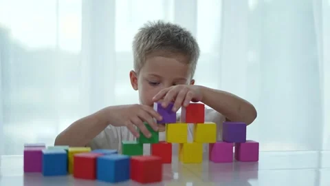 Focused child plays with blocks at table. Kindergarten activity scene. Child Vídeos de archivo 311621651