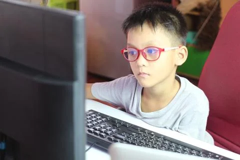 Focused Child Working on Computer in Indoor Setting Stock Photos