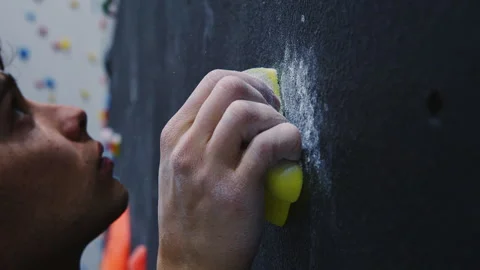Focused Climber with Chalk-Dusted Hands Gripping Large Hold on Indoor Climbing Stock Footage 276999821