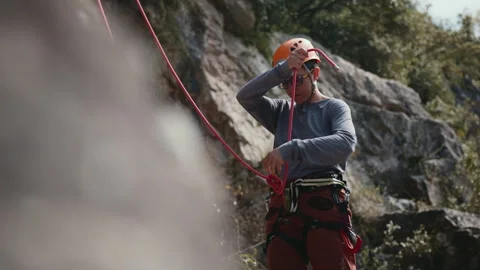 Focused Climber Preparing Gear for Ascent, Safety Checks Against Rocky Terrain Stock Footage 273800659