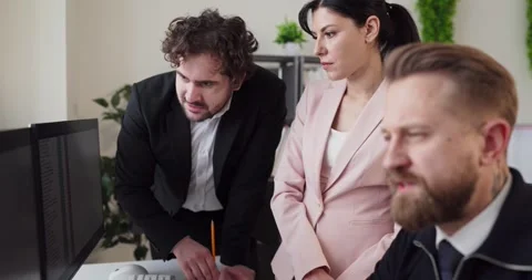 Focused colleagues reviewing project data on computer screens in meeting Stock Footage 338252257