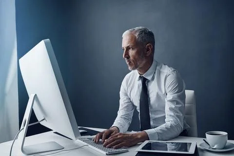 Focused on completing his task. a mature businessman working on his computer. Stock Photos