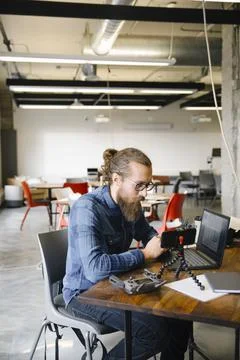 Focused computer programmer vlogging at laptop in office Stock Photos