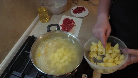 Focused cook adding chopped potato in a metallic pan Vidéo 342362926