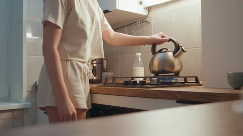 Focused cook lifting kettle as steam and scent fill space. An attentive home Stock Footage 342336337
