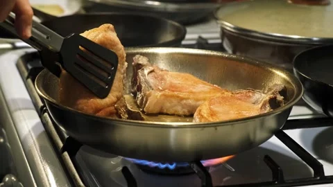 Focused cook methodically frying fish in a metallic pan on a gas stove with Stock Footage 339367335