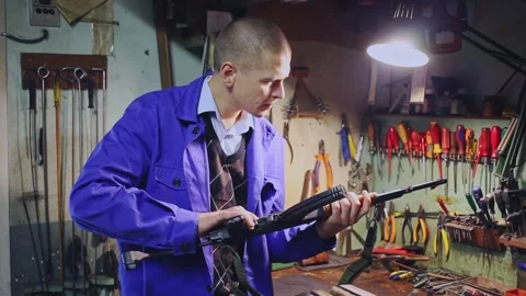 Focused craftsman of weapons workshop inspecting Kalashnikov assault rifle Stock Footage 150761229