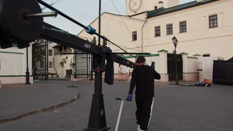 Focused crew guides heavy dolly carrying extended crane Stock Footage 321944666