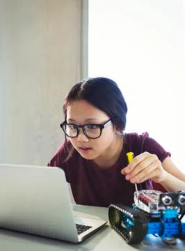 Focused, curious girl programming and assembling robotics at laptop in classroom Foto stock