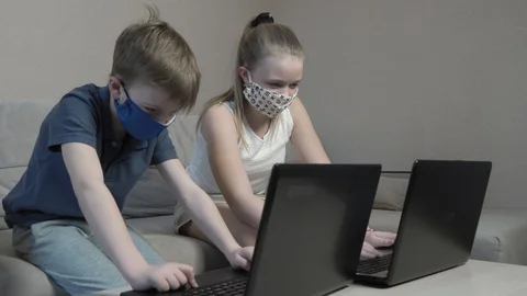 Focused cute boy and girl in protective mask using laptop search information Stock Footage 129357053