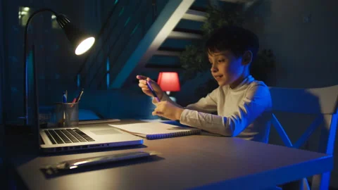 Focused Cute School Boy Studying at Table doing homework Listening Tutor by Stock Footage 154028425