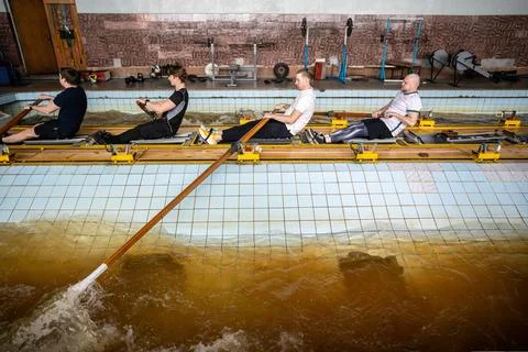 Focused determined athletes refine synchronized rowing, mastering oar control on Stock Photos