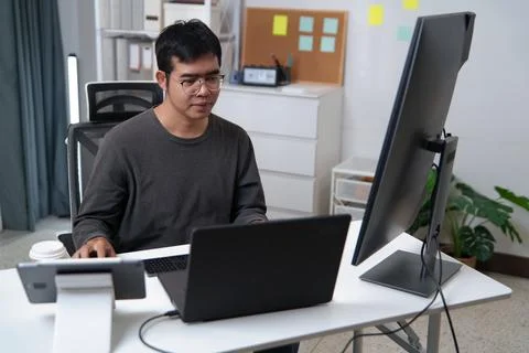 Focused Developer Working on Code with Multiple Monitors in Office Space 库存照片