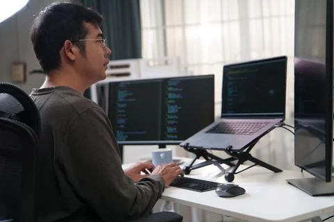 Focused Developer Working on Code with Multiple Computer Screens in a Tech Stock Photos