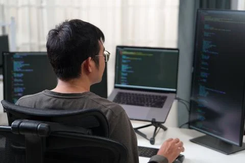 Focused Developer Working on Multiple Monitors for Software Programming and Stock Photos