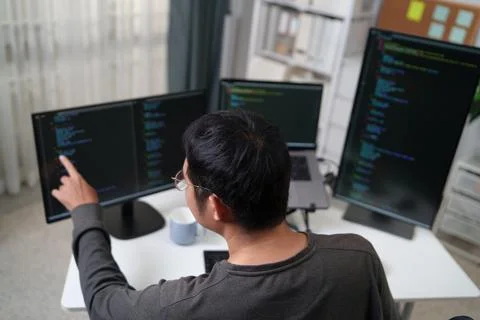 Focused Developer Working on Multiple Monitors with Code to Enhance Product.. Stock-Fotos