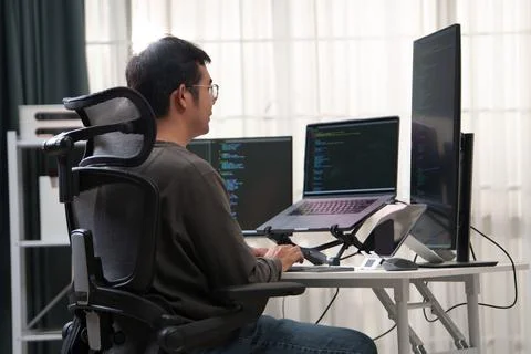 Focused Developer Working on Multiple Monitors at a Workspace with Advanced Stock Photos