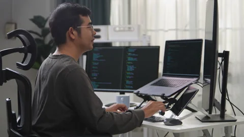 Focused Developer Working on Multiple Screens Displaying Code in a Remote E.. 動画素材 336680439