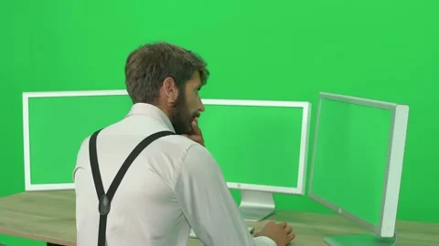Focused developer working on a PC while sitting at a desk, green background, a Stock Footage 237510994