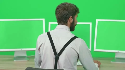 Focused developer working on a PC while sitting at a desk, green background, a Stock Footage 237682971