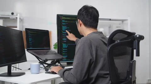 Focused Developer Working Remotely with Multiple Monitors Displaying Code a.. Stock Footage 336680242