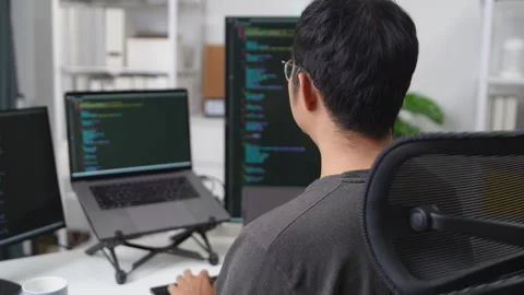 Focused Developer Working Remotely on Multiple Monitors with Coding Display.. Stock Footage 336680638