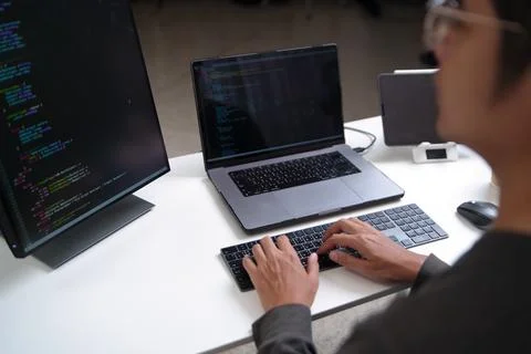 Focused Developer Working at a Workspace with Multiple Monitors for Programmi 库存照片