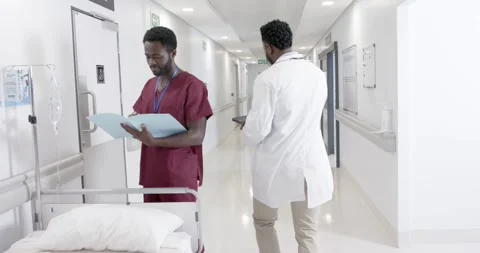 Focused diverse male doctors talking and female nurse with wheelchair in slow Stock Footage 336436222