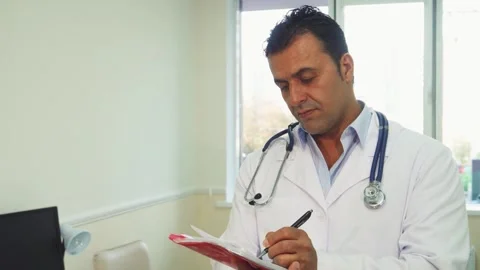 Focused doctor diligently notes patient information in his office Stock Footage 311992829