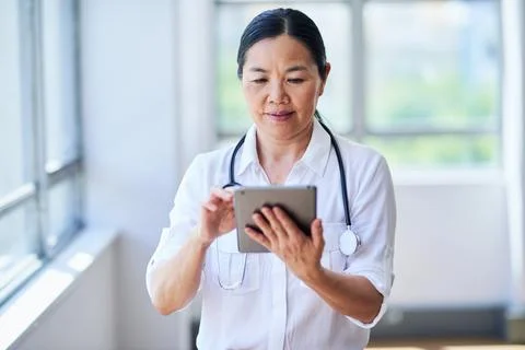 Focused Doctor Using Digital Tablet in Bright Hospital Setting Stock Photos