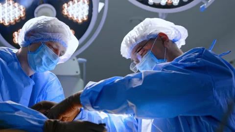 Focused doctors perform operation on the patient's heel. Cooperating surgeons in Stock Footage 342572838
