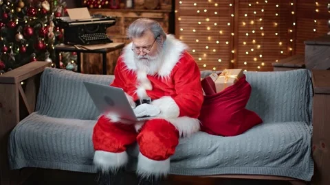 Focused elderly man in Santa Claus costume chatting use laptop. Wide shot on RED Stock Footage 147069095