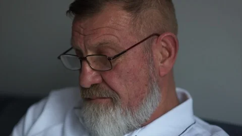 Focused elderly man using his smartphone on a sofa. Close-up, hands and face. A Video stock 121448309