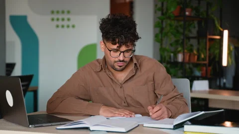 Focused employee taking notes and typing on laptop in modern office Stock Footage 312842463