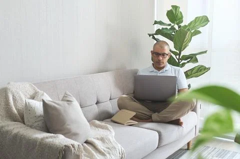Focused employee working remotely from home using laptop on sofa Foto stock