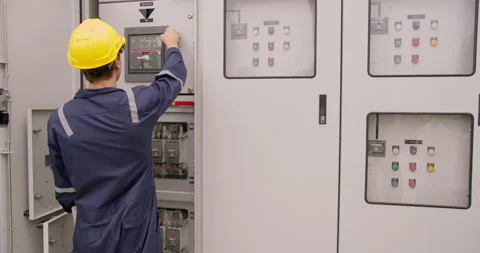 Focused engineer in a hard hat precisely operates an outdoor electrical control  Stock Footage 328595972