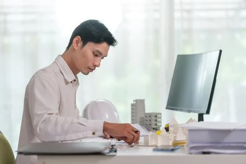 Focused engineer man inspecting architectural plan of new building in brigh.. Stock Photos