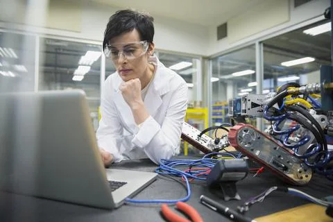 Focused engineer using laptop in robotics factory Stock Photos