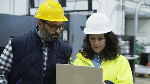 Focused engineers discussing work while standing with laptop Stock Footage 127348860