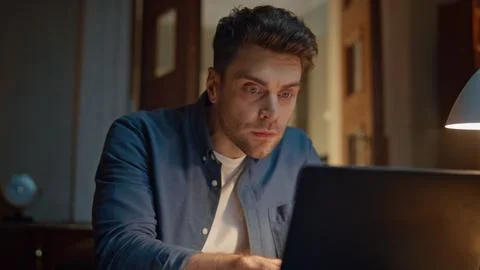 Focused entrepreneur typing computer at dark flat closeup. Man reacting failure Stock Photos