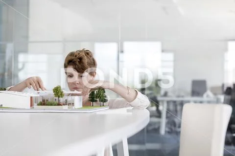 Focused female architect arranging model in conference room Stock Photos