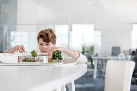 Focused female architect arranging model in conference room Stock Photos
