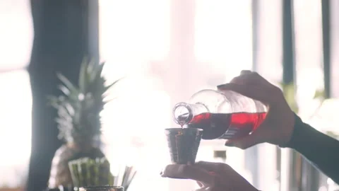 Focused female bartender pouring shots of liquor into a cocktail shaker in inter Stock Footage 199463547