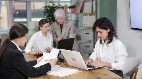 Focused female colleagues collaborating and using computers during a busy Stock Footage 341431324