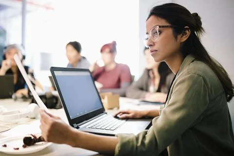 Focused female computer programmer coding at laptop in office 写真素材