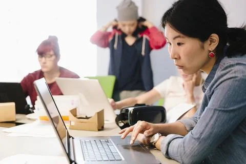 Focused female computer programmer coding at laptop in office Stock Photos