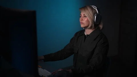 Focused female gamer using computer in home with headphones plying online video Stock Footage 275591128