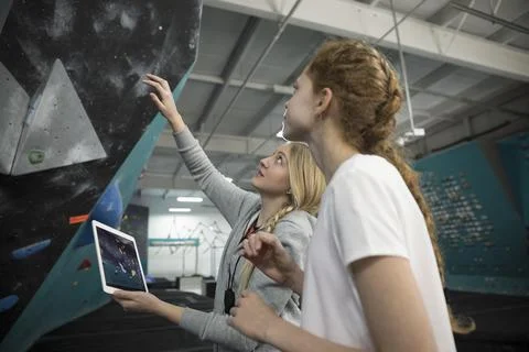 Focused female instructor with digital tablet guiding girl rock climber student Stock Photos