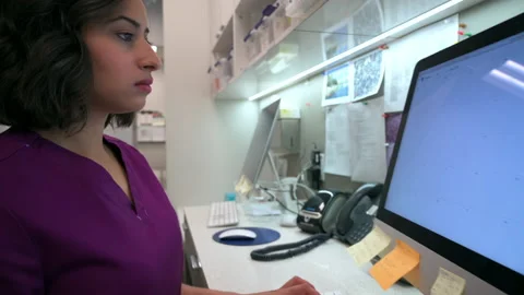 Focused female nurse using computer at clinic nurses station Stock Footage 220415973