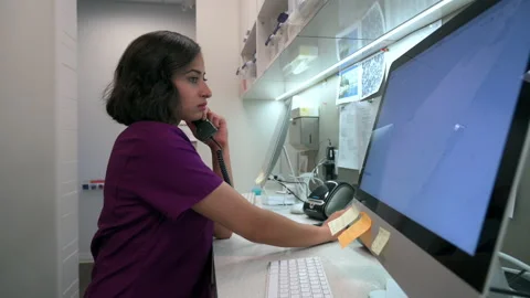 Focused female nurse working at computer and using telephone at clinic nurses st Video stock 220415838